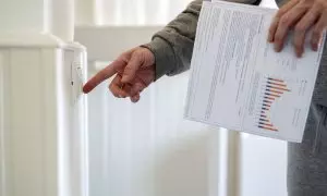 Un hombre enciende un interruptor con una factura de luz en la mano.