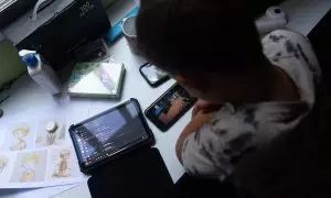 Un niño usa el teléfono móvil y una tablet, a 18 de octubre de 2023, en Madrid (España).