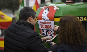 Dos manifestantes colocan un cartel contra el presidente del Gobierno mientras protestan en Ciudad Real para reclamar una agricultura más rentable que les permita hacer sostenibles en el futuro sus explotaciones agrarias y ganaderas.