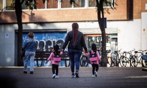 Una noia acompanya dues criatures per un carrer de Barcelona