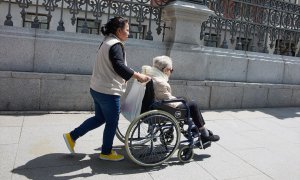 Una mujer mayor en silla de ruedas y su cuidadora pasean por el centro de la ciudad, a 4 de junio de 2023, en Madrid.