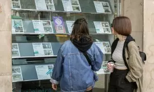 Dos personas observan la oferta de pisos en alquiler de una oficina inmobiliaria de Barcelona, a 12 de marzo de 2024.