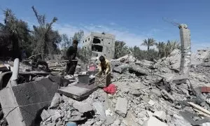 15/03/2024 Varios palestinos tratan de recoger sus pertenencias utilizables alrededor de los restos tras un ataque israelí en Dair El-Balah, Gaza, a 13 de marzo de 2024.