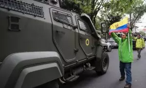 Un hombre exhibe una bandera mientras pasa un vehículo blindado donde es trasladado el exvicepresidente ecuatoriano Jorge Glas