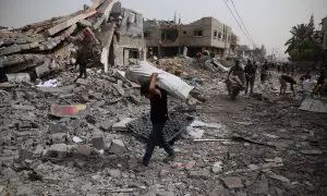 Un hombre transporta objetos recogidos entre los escombros en el campo de refugiados de Nuseirat, en el centro de la Franja de Gaza, a 18 de abril de 2024.