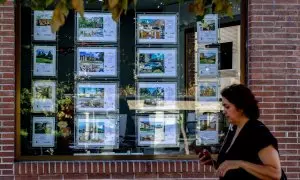 Una mujer camina frente a un escaparate de anuncios de viviendas, a 4 de agosto de 2023, en Madrid.