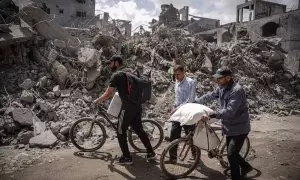 28/04/2024 Palestinos caminan frente a la destrucción en el campo de Nuseirat, en la Franja de Gaza, a 27/04/2024.