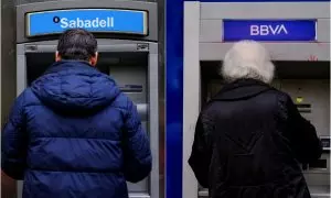 Dos personas usan los cajeros del BBVA y del Banco Sabadell en imágenes de archivo.