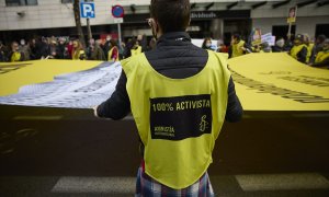 Varias personas portan una banderola amarilla gigante de Amnistía Internacional  en una manifestación, a 13 de febrero de 2022, en Madrid.