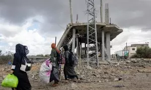 Palestinas desplazadas portan sus pertenencias en Rafah después de la orden de evacuación del ejército israelí.