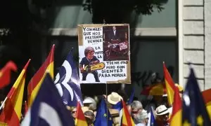 Una persona sujeta un cartel de protesta durante una manifestación del PP, en la Puerta de Alcalá, a 26 de mayo de 2024, en Madrid.