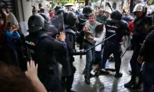 Un home intenta protegir una dona dels cops de porra d'agents antidisturbis de la policia espanyola l'1 d'octubre d'aquest 2017.