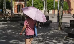 23 de julio de 2024. Una mujer con paraguas por las altas temperaturas paseando por Sevilla el 23 de julio de 2024.