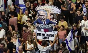 Un manifestante sostiene un cartel con una caricatura del primer ministro israelí, Benjamin Netanyahu, en el que se puede leer "La trampa de Michel Platini", mientras miles de manifestantes que apoyan a las familias de los rehenes israelíes retenidos por