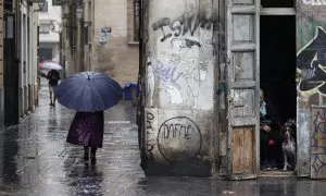 Una persona camina bajo la lluvia por las calles del centro histórico de València.