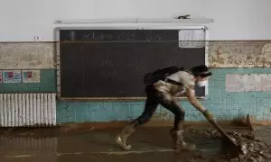 Una mujer limpia una de las aulas del colegio de Sedaví, lleno de barro tras la DANA.