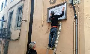 Els operaris tapant la placa dedicada a Ortega Monasterio per l'altra a favor dels drets de les dones arran del 25-N