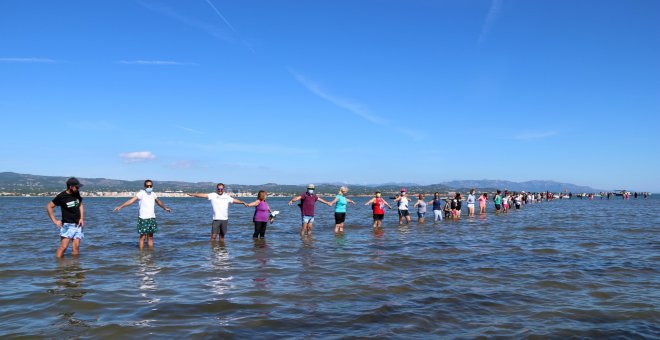 Centenars de persones fan una cadena humana a la badia del Fangar per denunciar la regressió del delta de l’Ebre