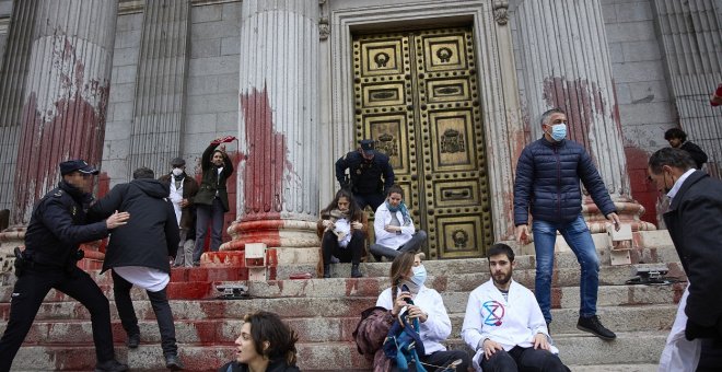 Científicos y activistas tiñen de rojo la entrada del Congreso en protesta por la inacción ante la emergencia climática