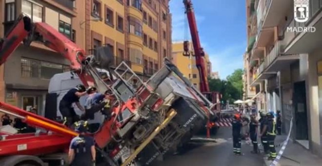 Los bomberos consiguen recuperar con una grúa un camión en el centro de Madrid