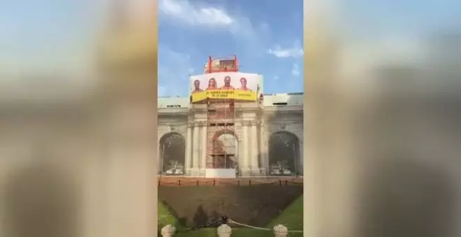 La Puerta de Alcalá amanece tapada por una pancarta con la cara de los candidatos y la frase: "¿El cambio climático os la suda?"